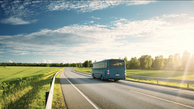 Autobuss brauc pa asfaltētu lauku ceļu skaistā pavasara dienā